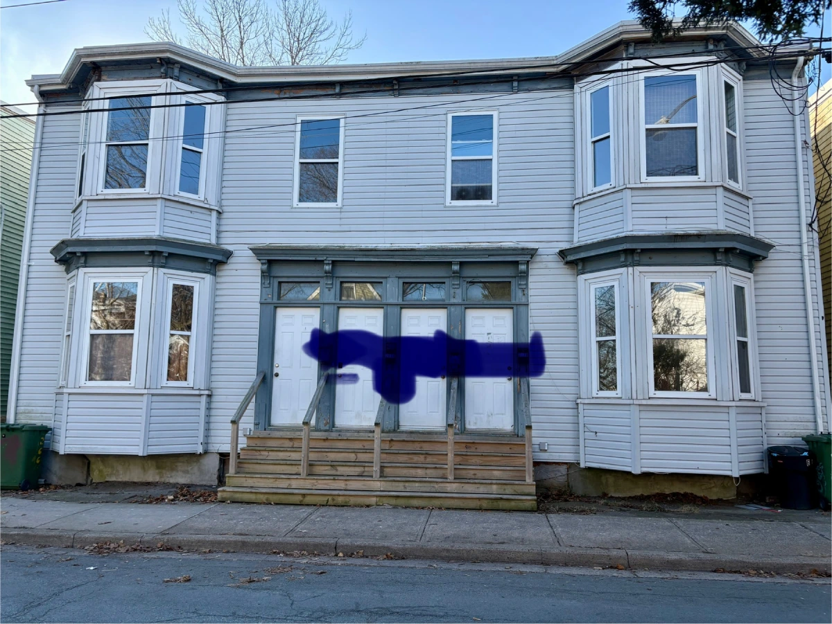 Image of a white siding four-plex with four white doors. A large, horizontal, dark blue spray paint streak crosses the four doors.