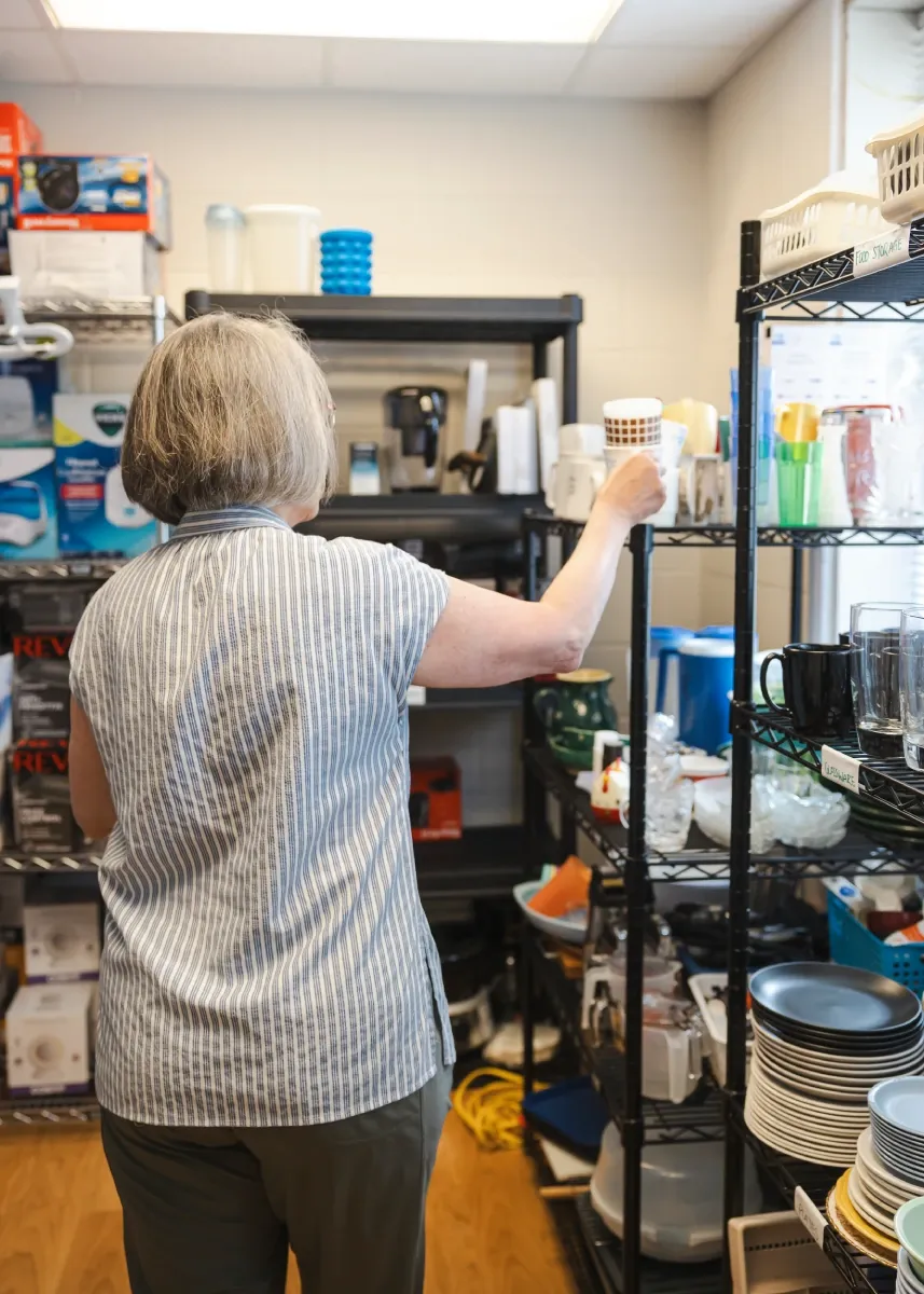 A volunteer is organizing donations in a storage room.