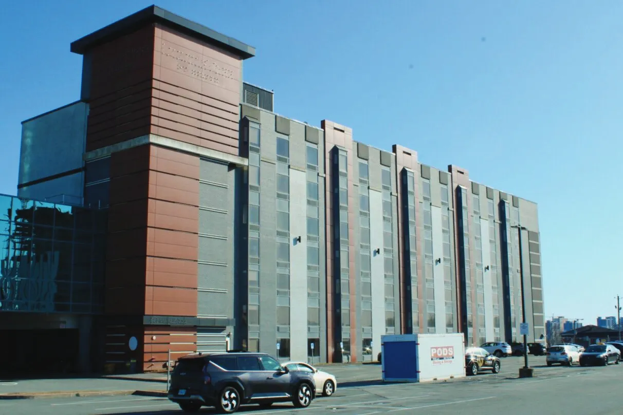 A large hotel-like building is pictured. Cars and a parking lot are photographer in the freoground.